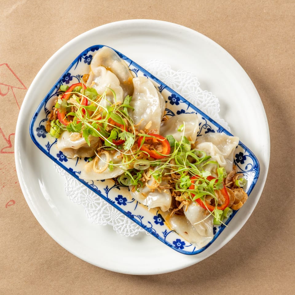 Orienta Restaurant's dumplings, garnished with fresh herbs, red peppers, and crispy fried onions.